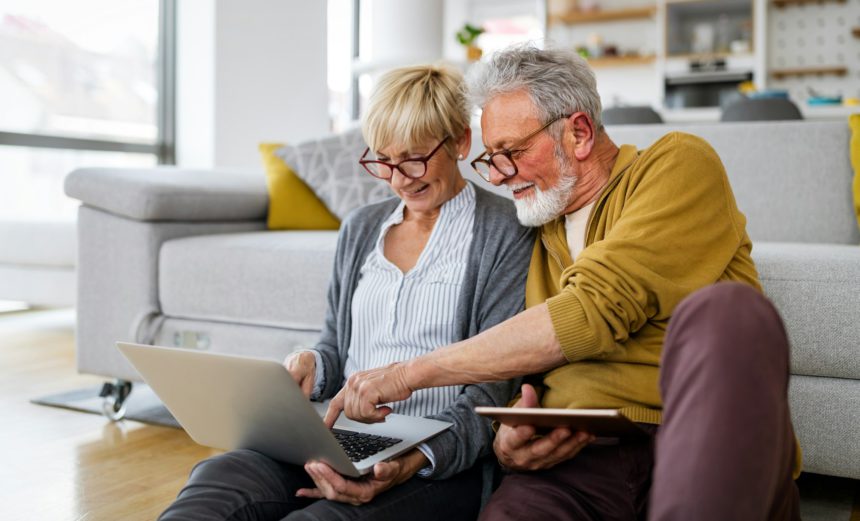 Cheerful senior couple using technology devices and having fun at home