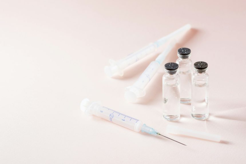 Vaccination and Immunization. Open syringe in front of glass vials with vaccine and clean syringes