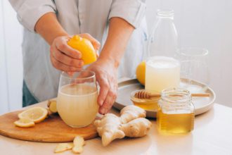 Woman prepares drink from fresh ginger root lemon honey. Health antioxidant herbal vitamins