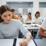 Woman, student and writing university exam in classroom for higher education, scholarship and train