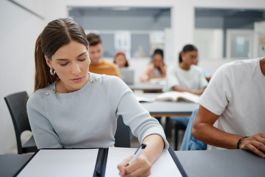 Woman, student and writing university exam in classroom for higher education, scholarship and train